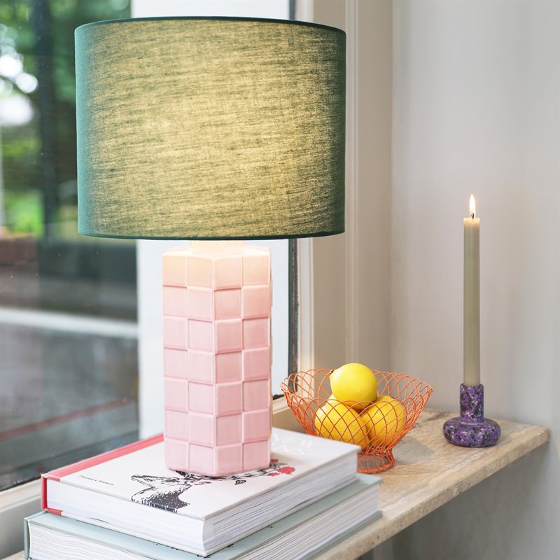 &klevering pink check lamp with green shade placed on stacked books beside a window
