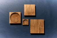 Four HKLIVING teak cube bowls and trays in varying sizes shown from above against a dark blue background
