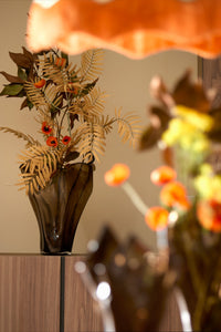 Aiora vase in dark brown holding decorative branches on wooden cabinet