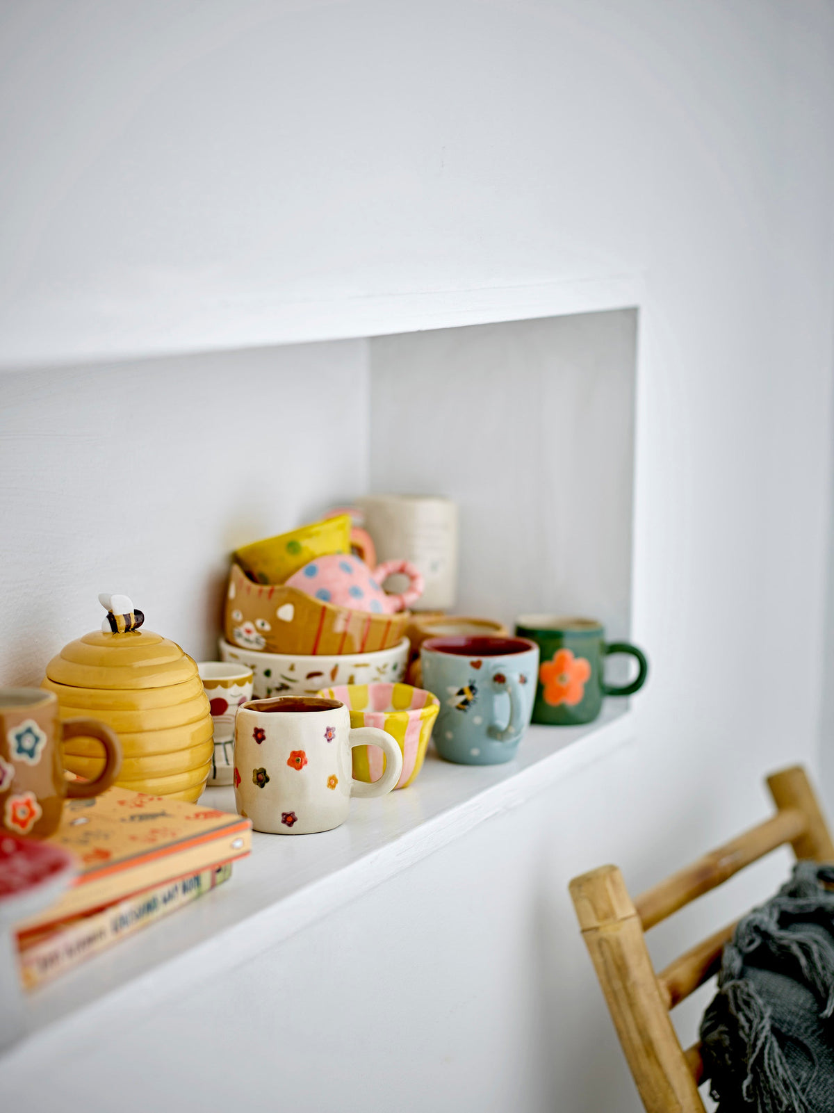 Addy cups with colourful hand-painted flowers displayed on a kitchen shelf
