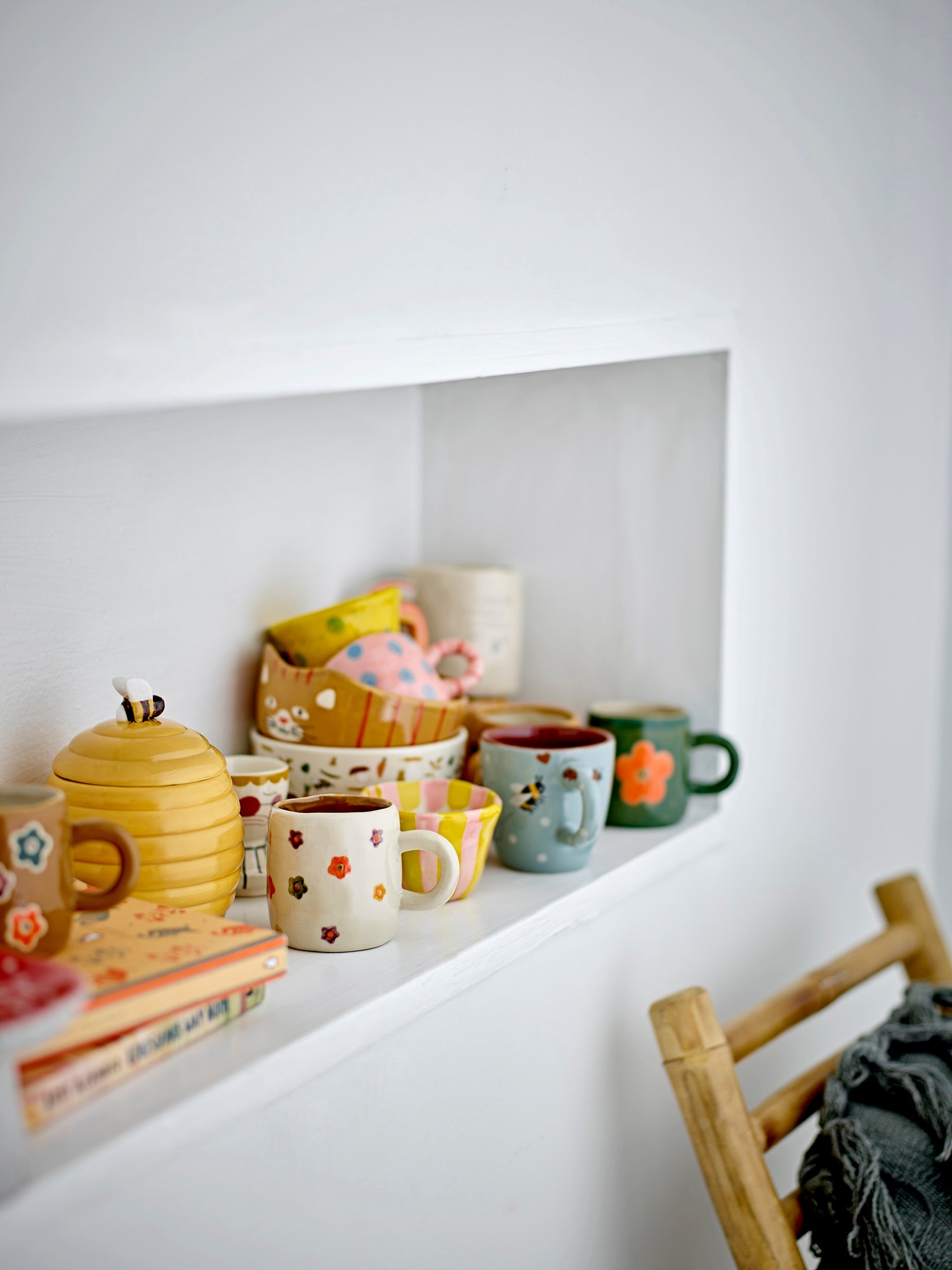 Addy cups with colourful hand-painted flowers displayed on a kitchen shelf
