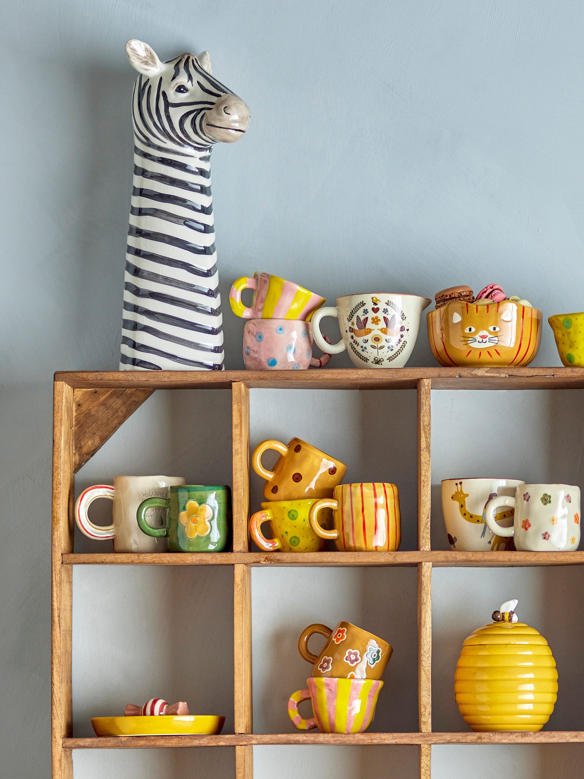 Addy cups with dark green glaze and colourful flowers displayed on a kitchen shelf
