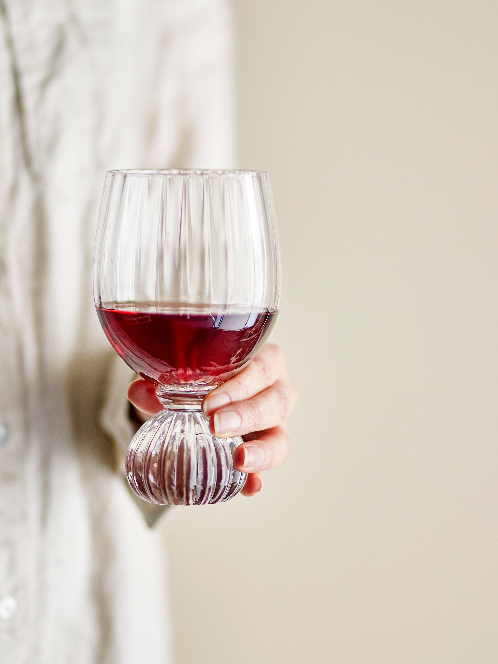 Taurin wine glass with ribbed bowl and round base, held in hand with red wine, 430ml
