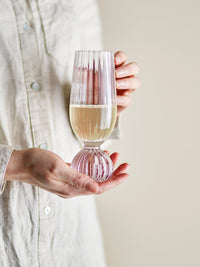 Taurin champagne glass with ribbed bowl and round base, held in hand with champagne, 250ml
