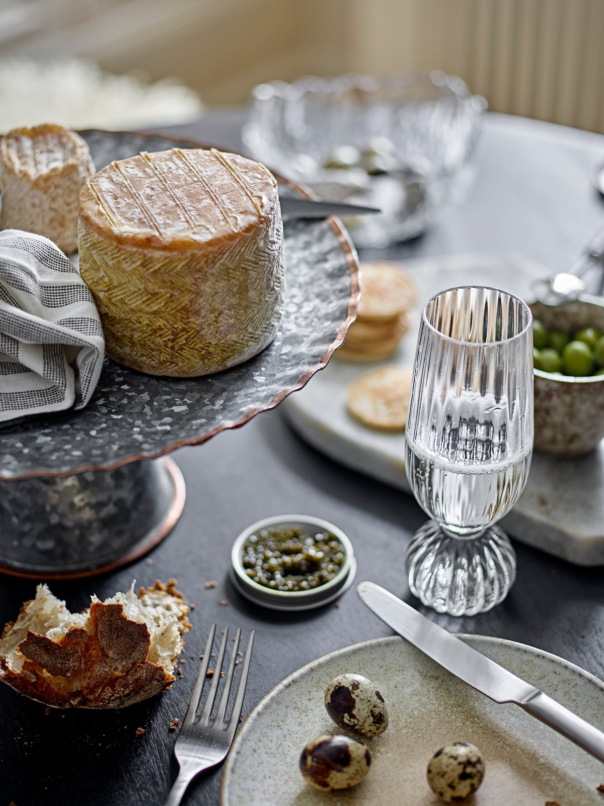 Taurin champagne glass styled on a dining table with cheese, olives, and matching glassware
