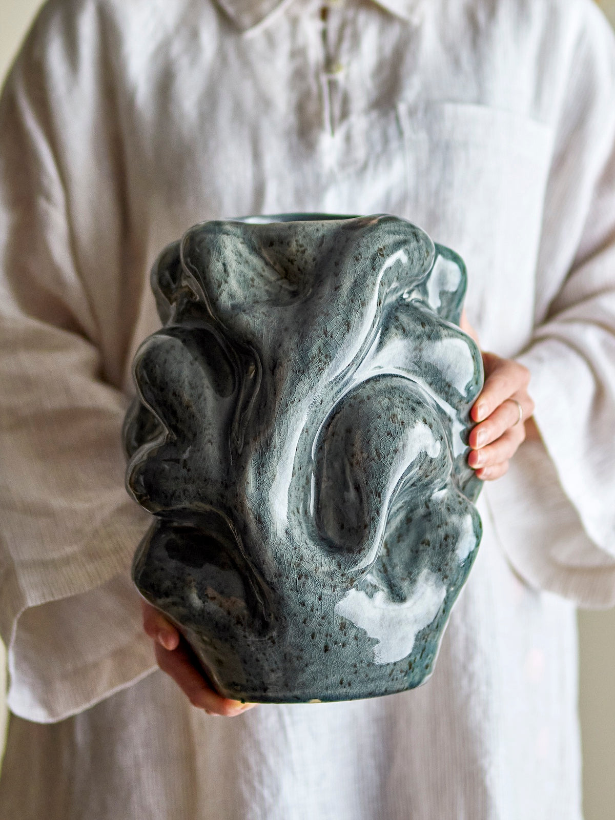 Close up of Vuelle vase held by hand showing reactive glaze texture
