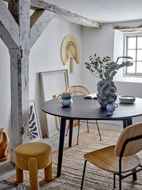 Dining room with a black round table, wooden chairs, and decorative elements.