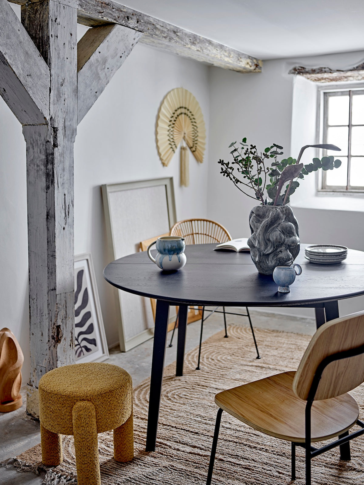 Dining room with a black round table, wooden chairs, and decorative elements.