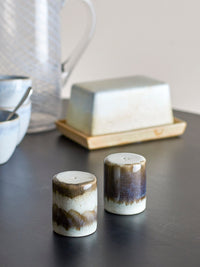close-up of grey reactive-glaze Paula salt and pepper shakers on a dark tabletop