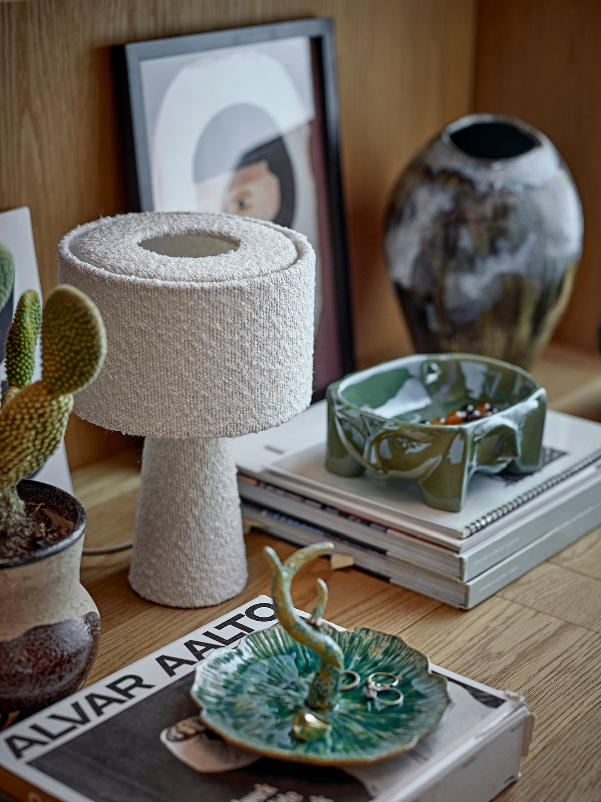 Amilia bowl in green reactive glaze stoneware with face motifs, styled on a shelf
