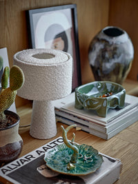 Amilia bowl in green reactive glaze stoneware with face motifs, styled on a shelf
