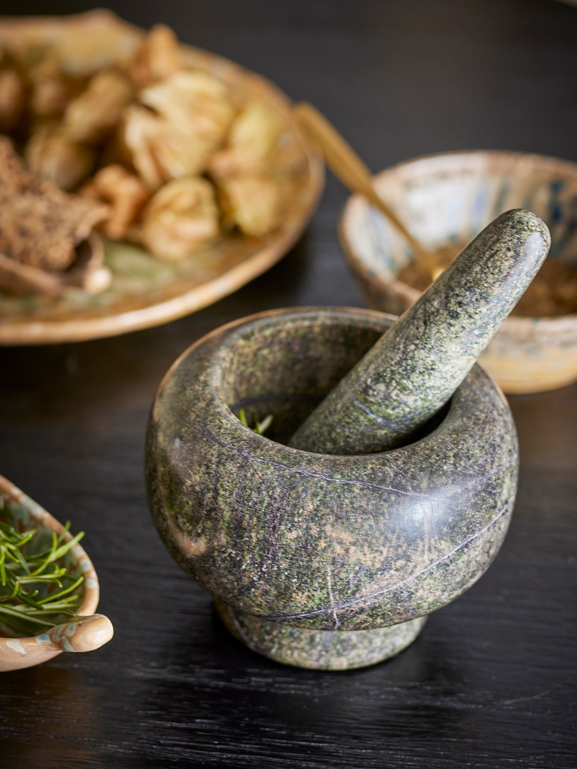 Mortar and pestle with herbs on a dark surface