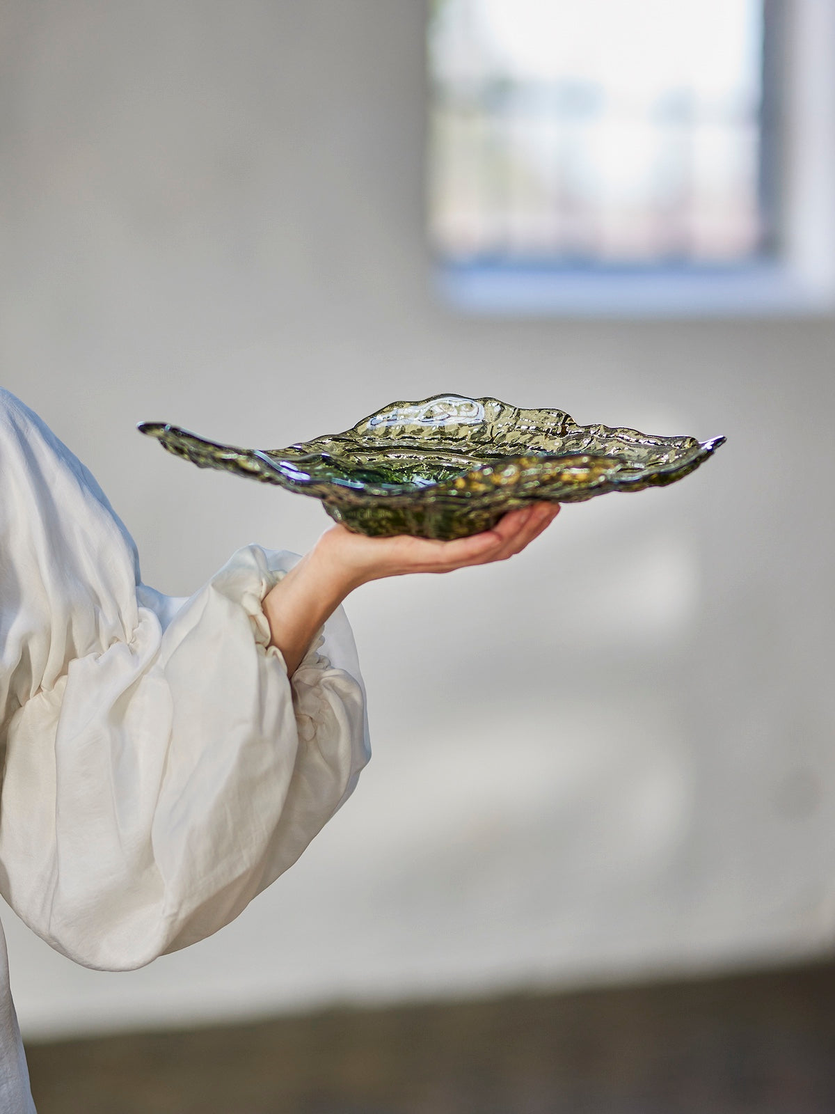 Aiku olive green glass bowl held in hand showing rippled oyster shell shape