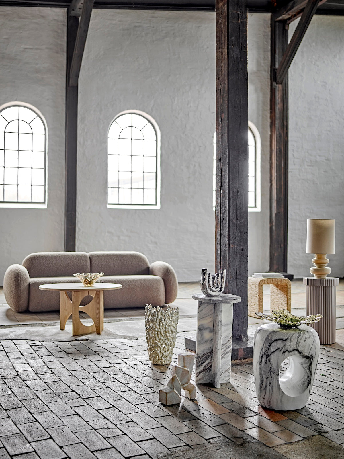 Modern interior design with marble and stone furniture in a large room with high ceilings and arched windows.