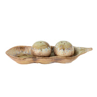 Front view of the Kayo salt and pepper shakers sitting in the wavy olive green pea pod tray on a white background