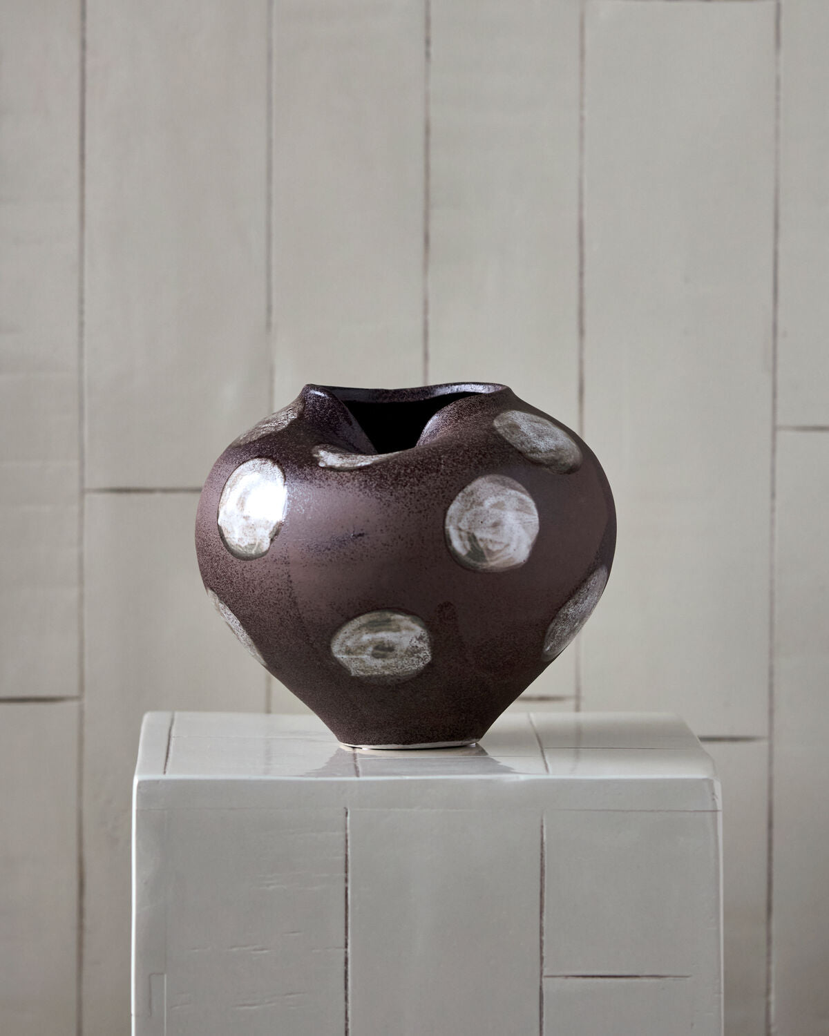 House Doctor Expo vase styled on a white plinth against a pale tiled wall, a sculptural focal point for entryways and modern bohemian interiors