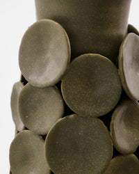 Close-up of the handmade ceramic discs applied to the House Doctor Dot vase, showing the matte speckled khaki glaze and tactile depth
