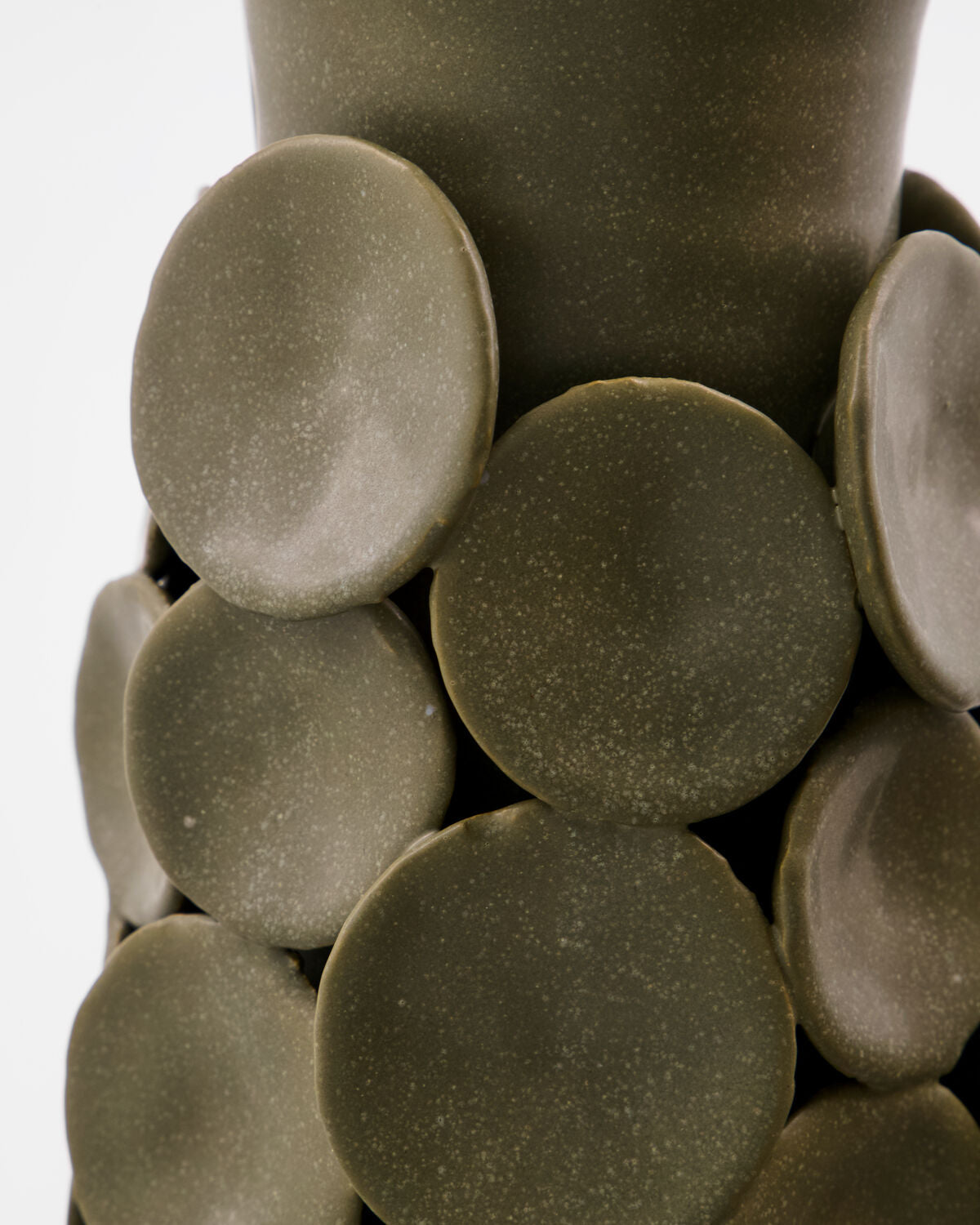 Close-up of the handmade ceramic discs applied to the House Doctor Dot vase, showing the matte speckled khaki glaze and tactile depth