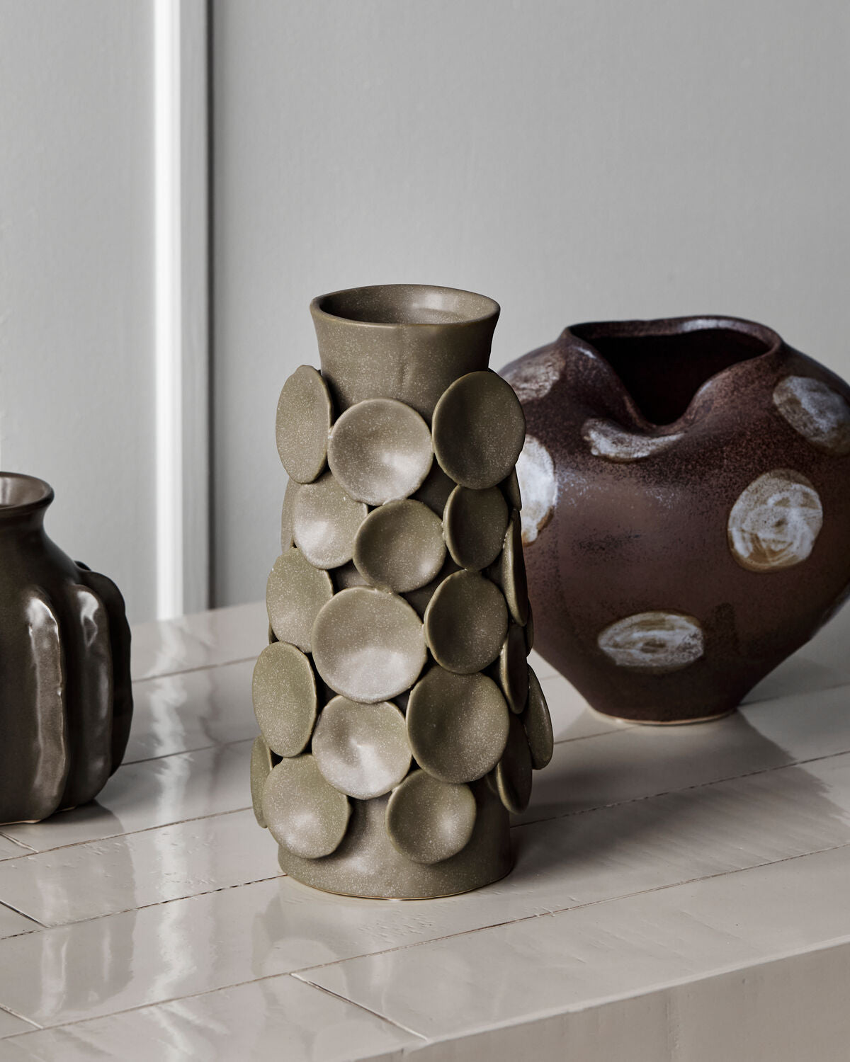 House Doctor Dot vase styled alongside the Expo vase and another stoneware piece, sculptural khaki and brown ceramics on a pale console for a layered shelf look