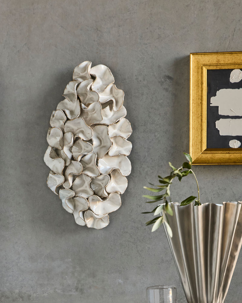 House Doctor Fold ceramic wall art styled on a warm grey wall beside a gold-framed artwork and silver fluted vase, a gallery-curated hallway moment