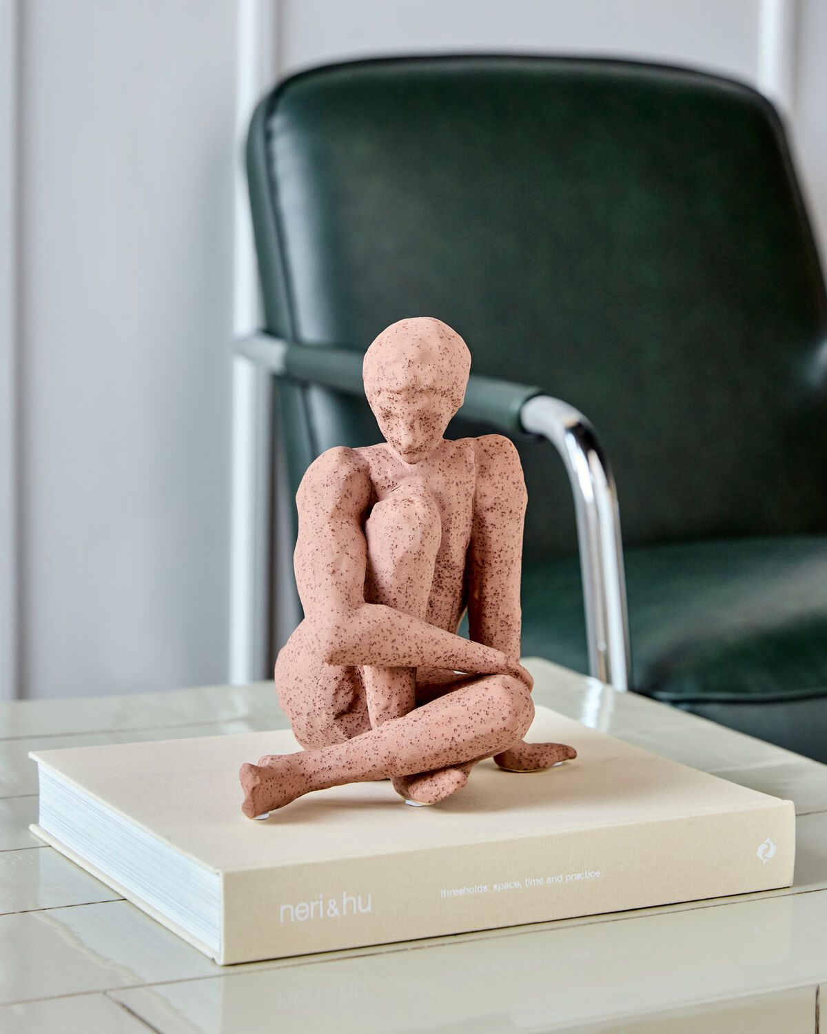 House Doctor Woman sculpture styled on a Neri and Hu coffee table book in front of a green leather chair, a contemplative decorative piece for design-led interiors
