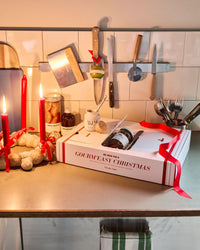 Nicolas Vahé Advent gift box 2026 opened on a festive kitchen counter with red candles, ribbon and the golden butter knife