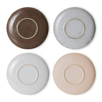the bottom of all 4 of the saucers in a redish brown, speckled grey, flat grey, and an almost pink hue to the final one