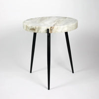 side view of the white marble side table with its 3 legs in black iron from swedish design studio olsson and jenssen