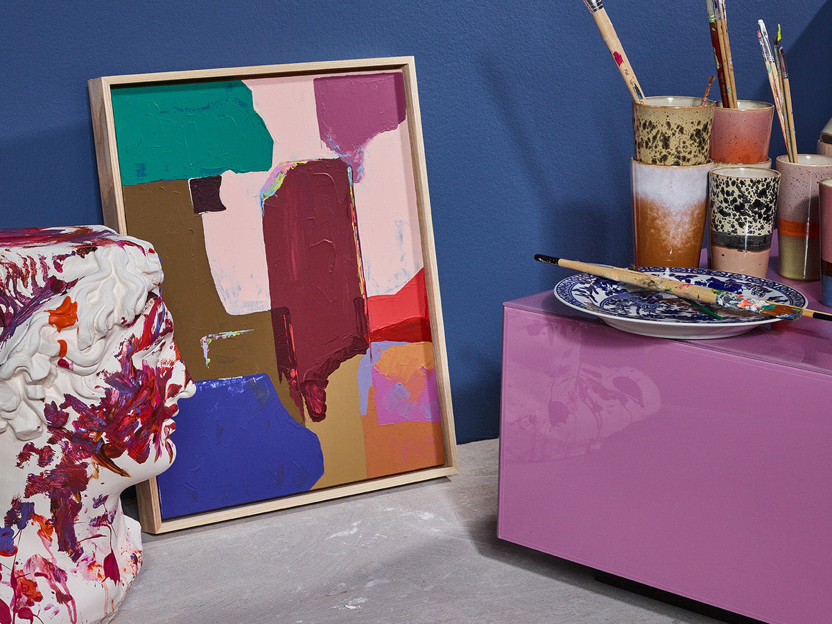 Pink HKLIVING mirror block table with a patterned armchair and abstract artwork