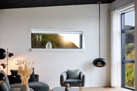 Modern living room with a large window, gray sofa, and armchair warmed by a Le Feu real flame fireplace.