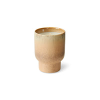 Beige ceramic cup with candle just visible on a white background