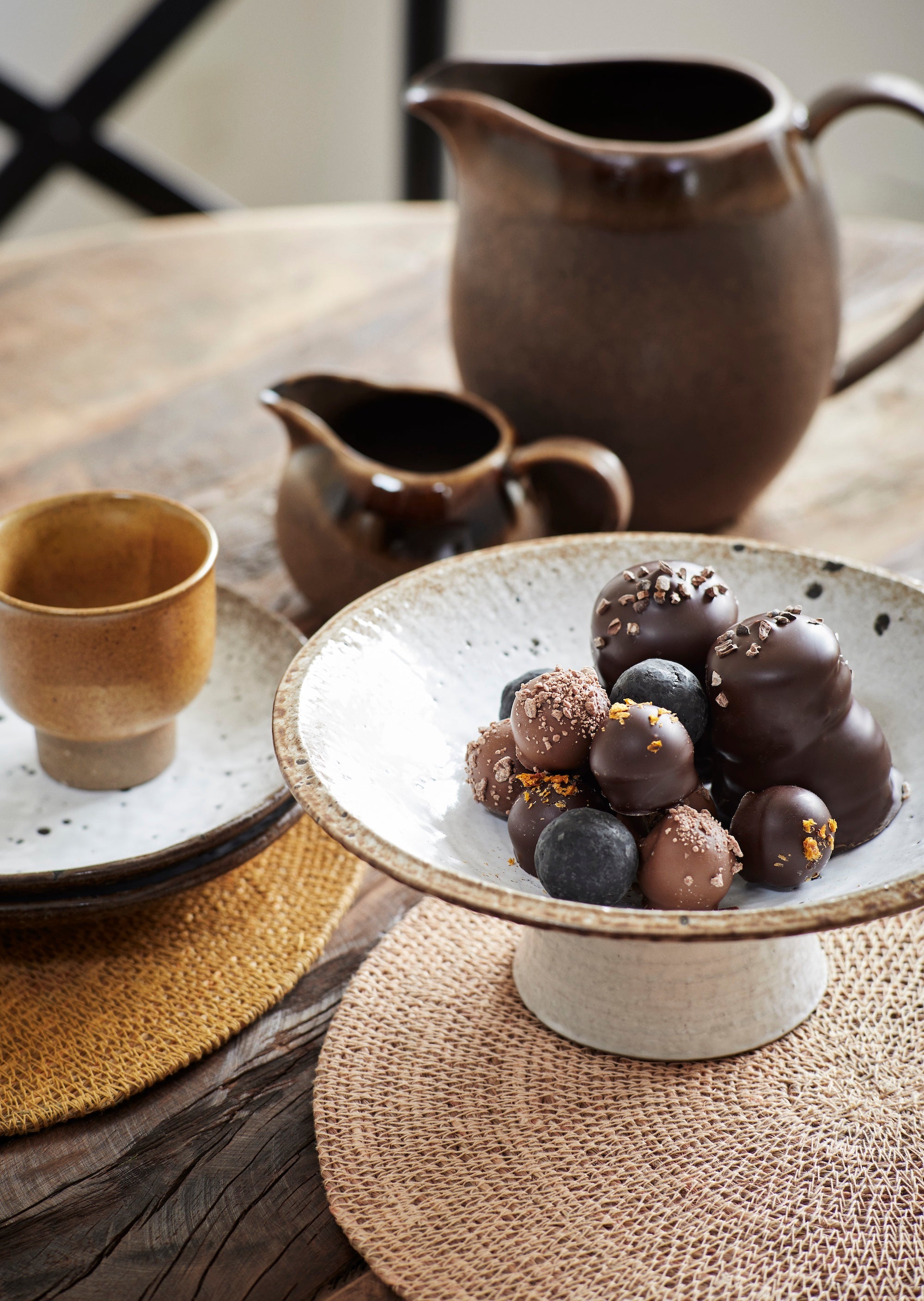 stoneware pedestal dish in beige and brown used as a fruit stand on a rustic table
