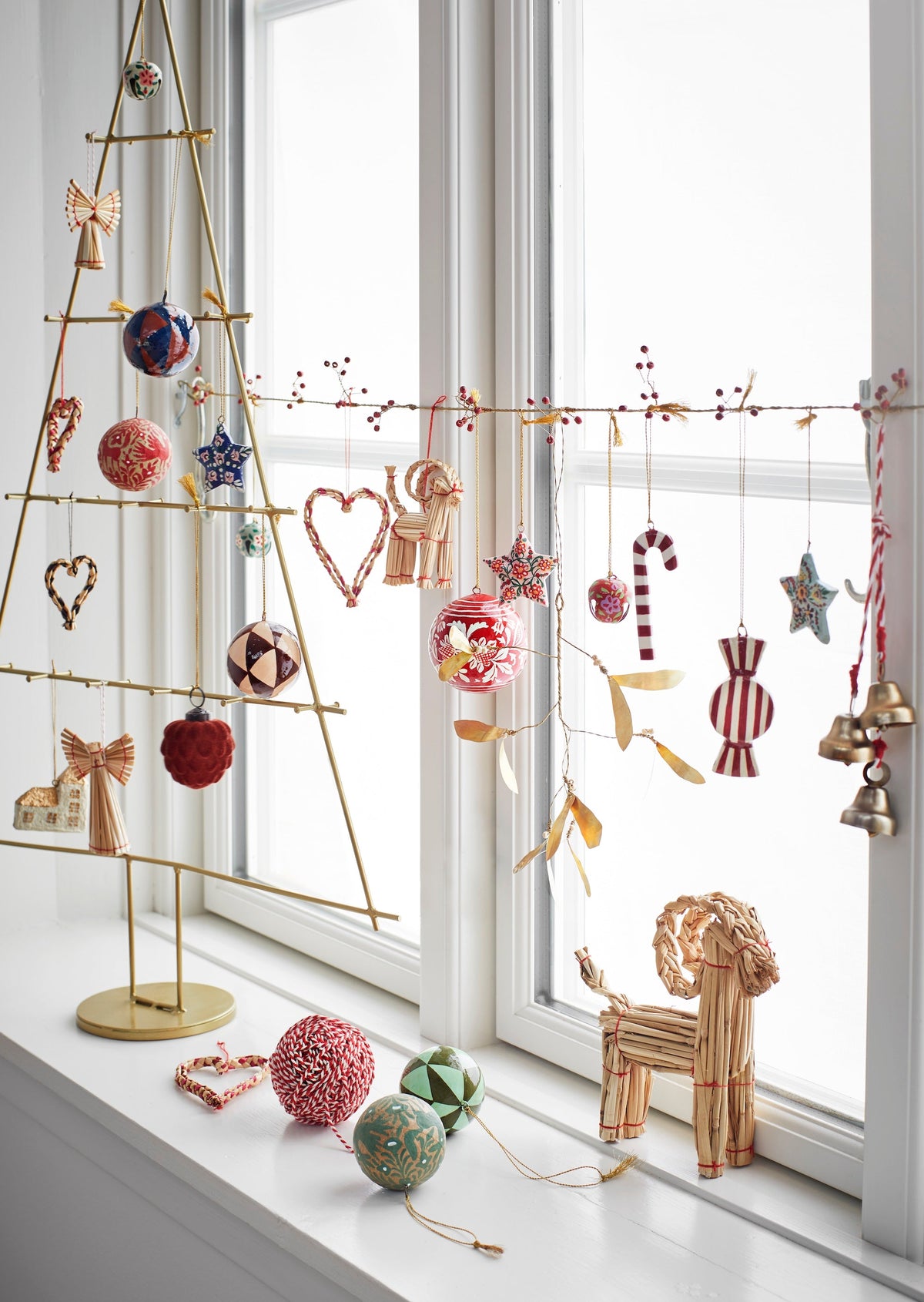 christmas window display with handmade folklore ornaments including striped red candy designs
