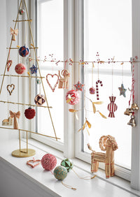 christmas window display with handmade folklore ornaments including striped red candy designs
