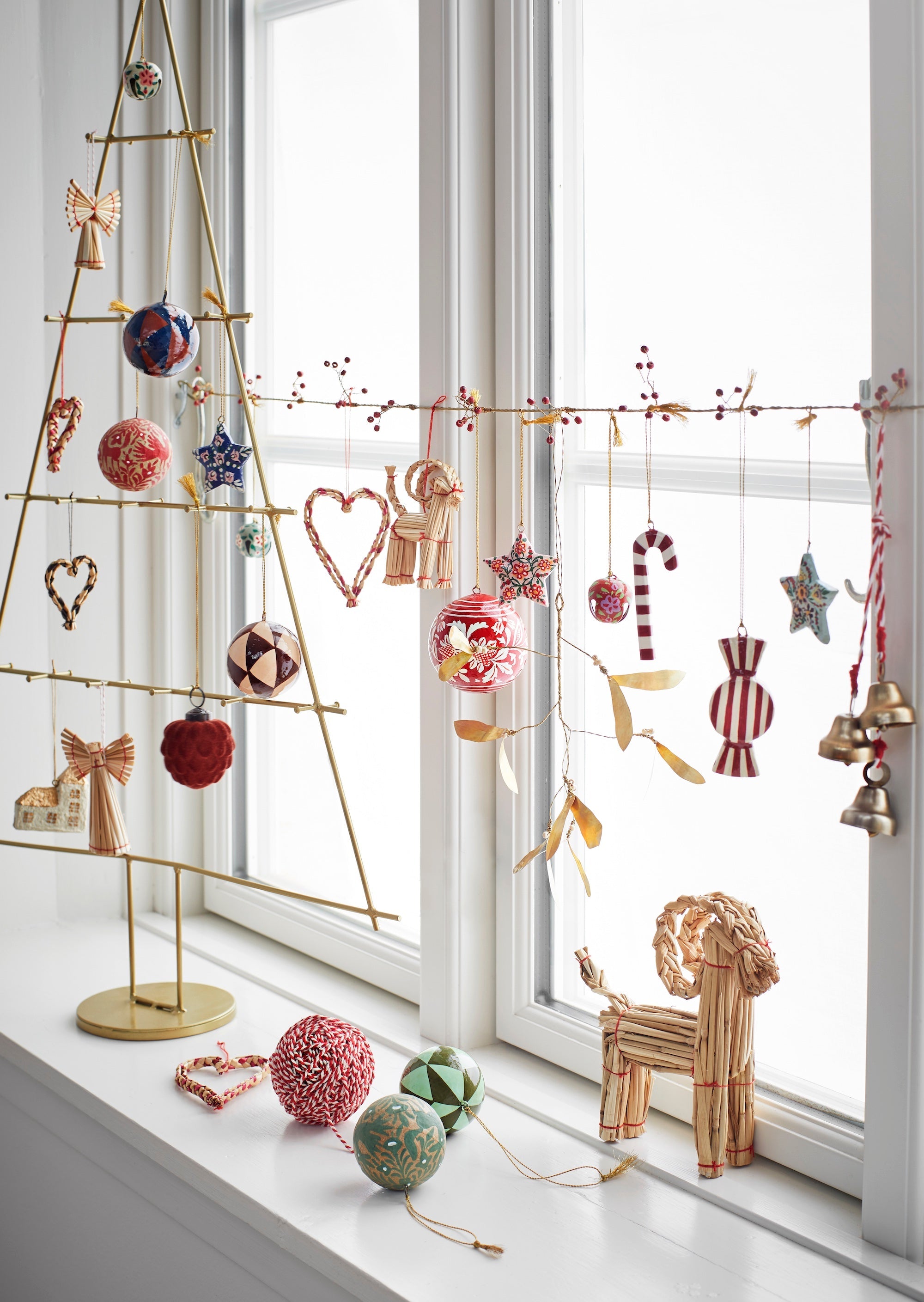 christmas window display with handmade folklore ornaments including striped red candy designs
