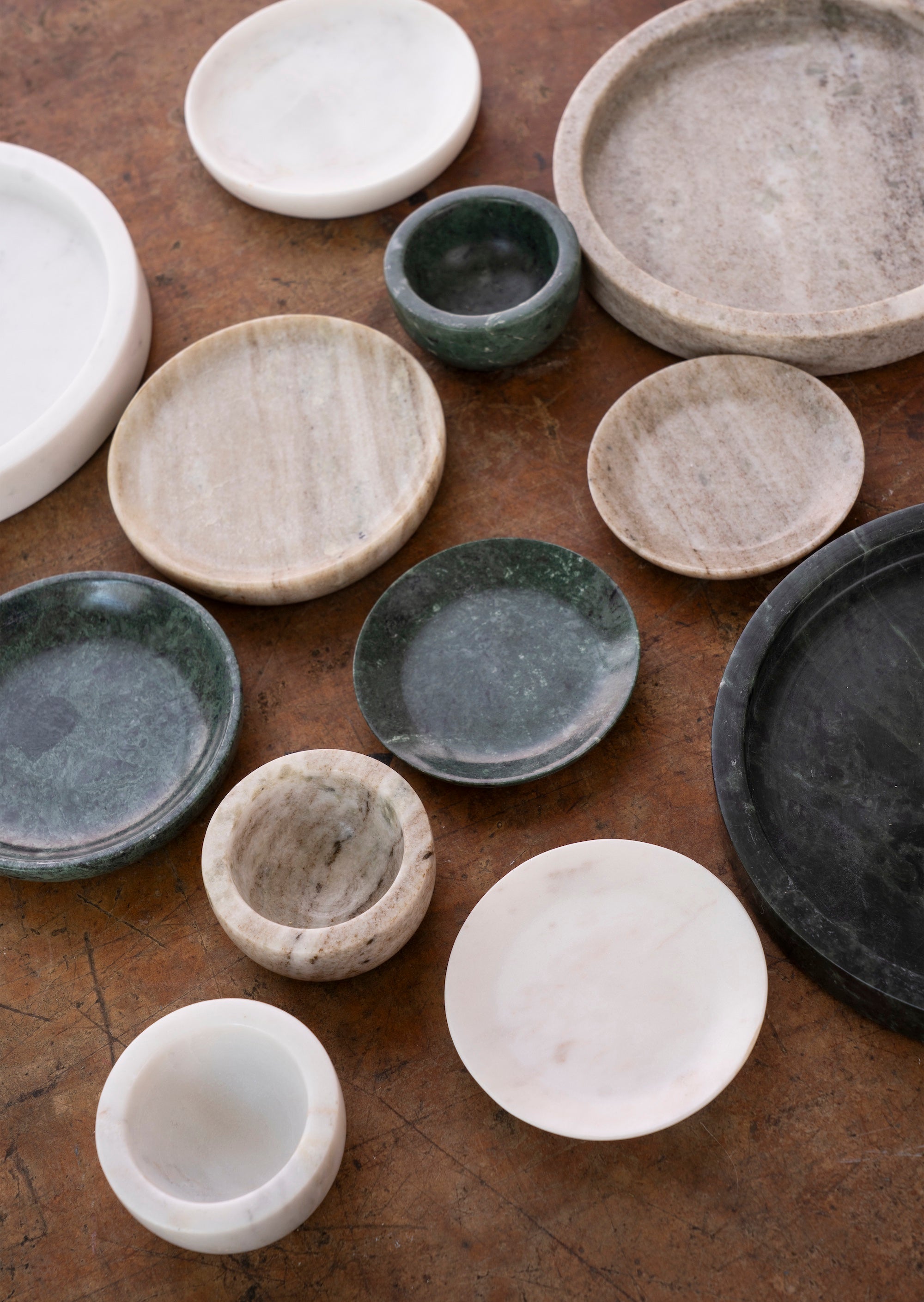 assorted marble bowls and dishes including dark green pinch pot styled on rustic table
