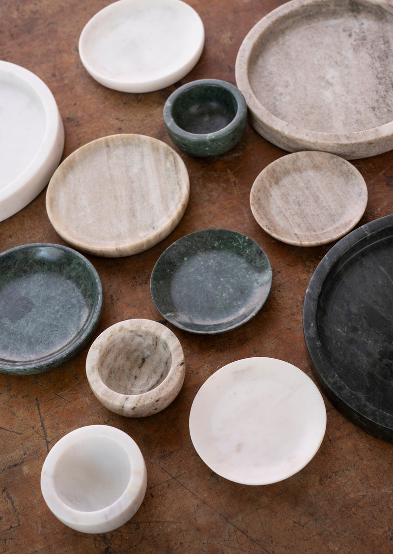 assorted marble bowls and dishes including dark green pinch pot styled on rustic table
