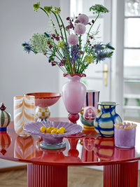 tall rose glass frills vase filled with flowers on modern red table

