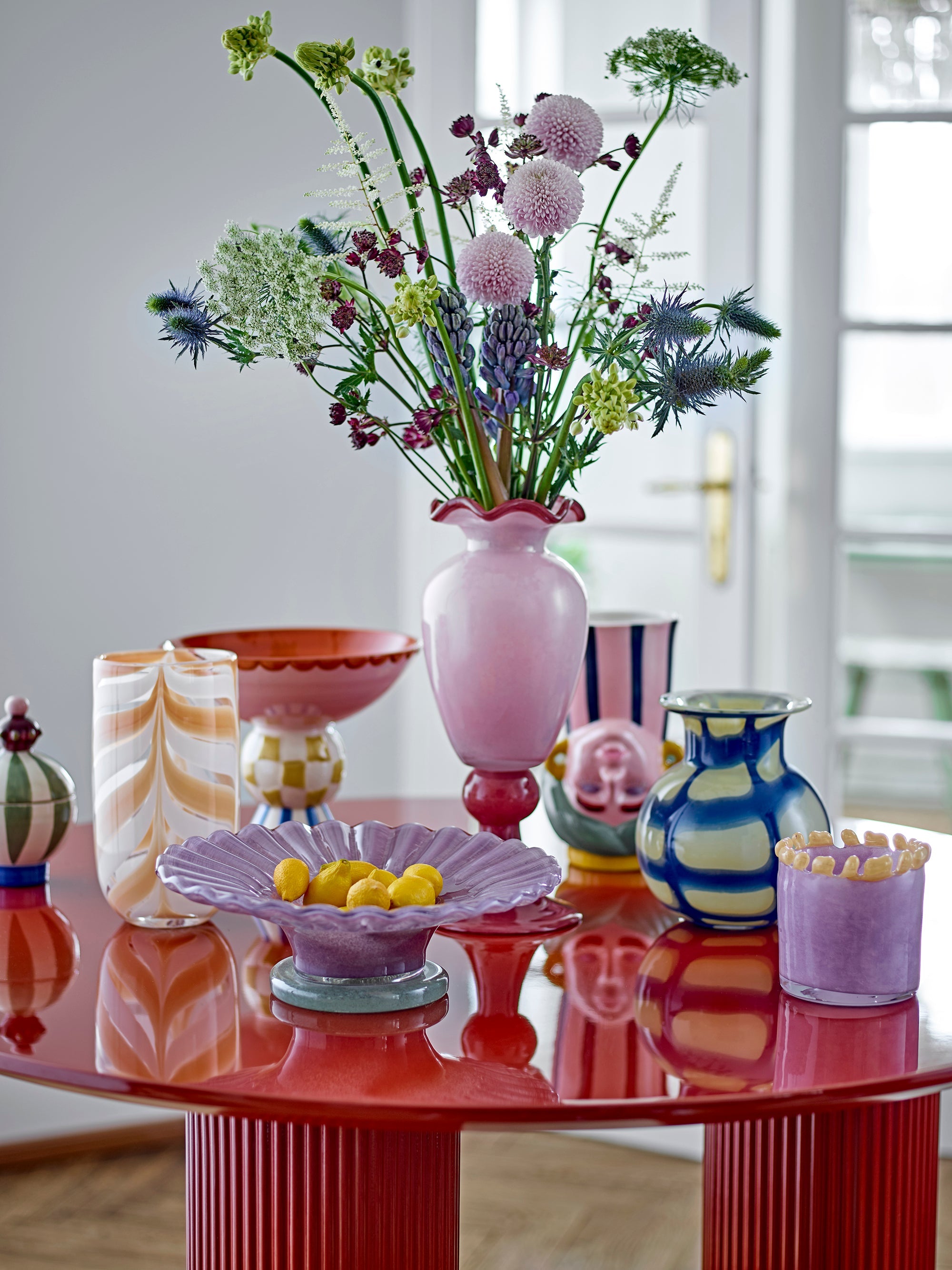 tall rose glass frills vase filled with flowers on modern red table
