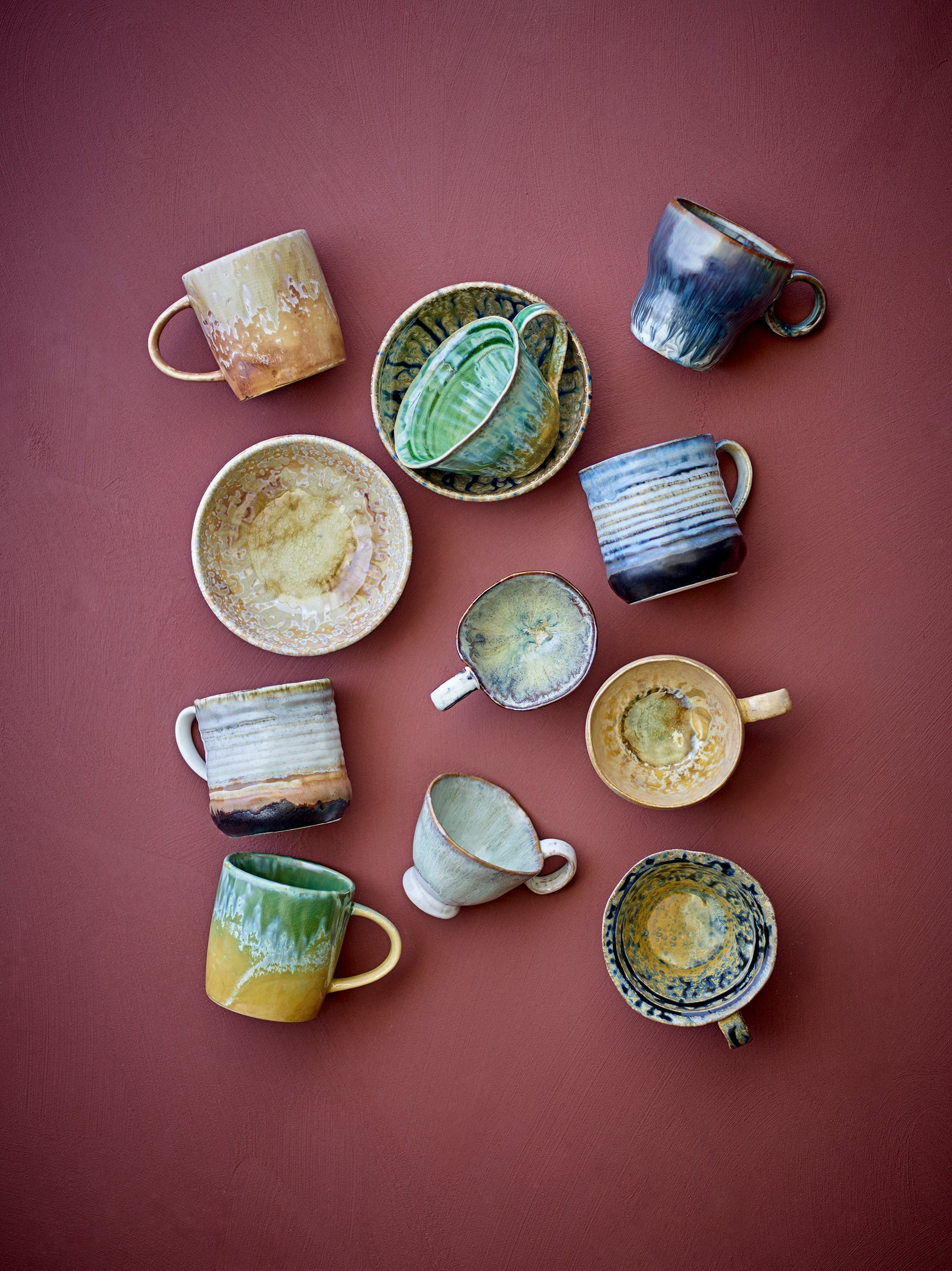 selection of reactive-glaze ceramic mugs including the green Bloomingville milani mug on a terracotta background
