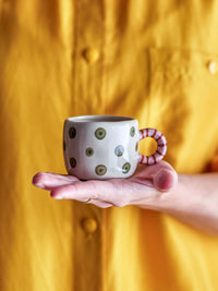 hand holding nature bloomingville nini cup with green dots and striped handle