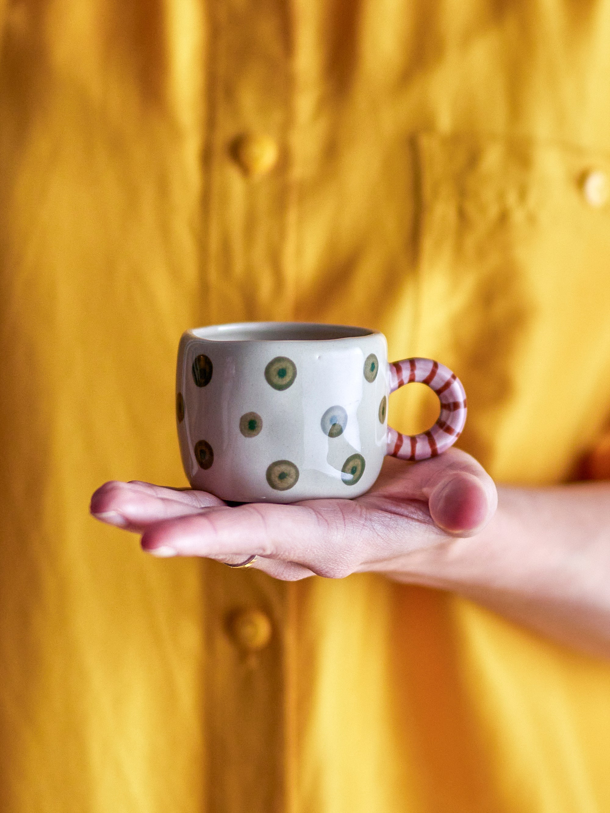 hand holding nature bloomingville nini cup with green dots and striped handle