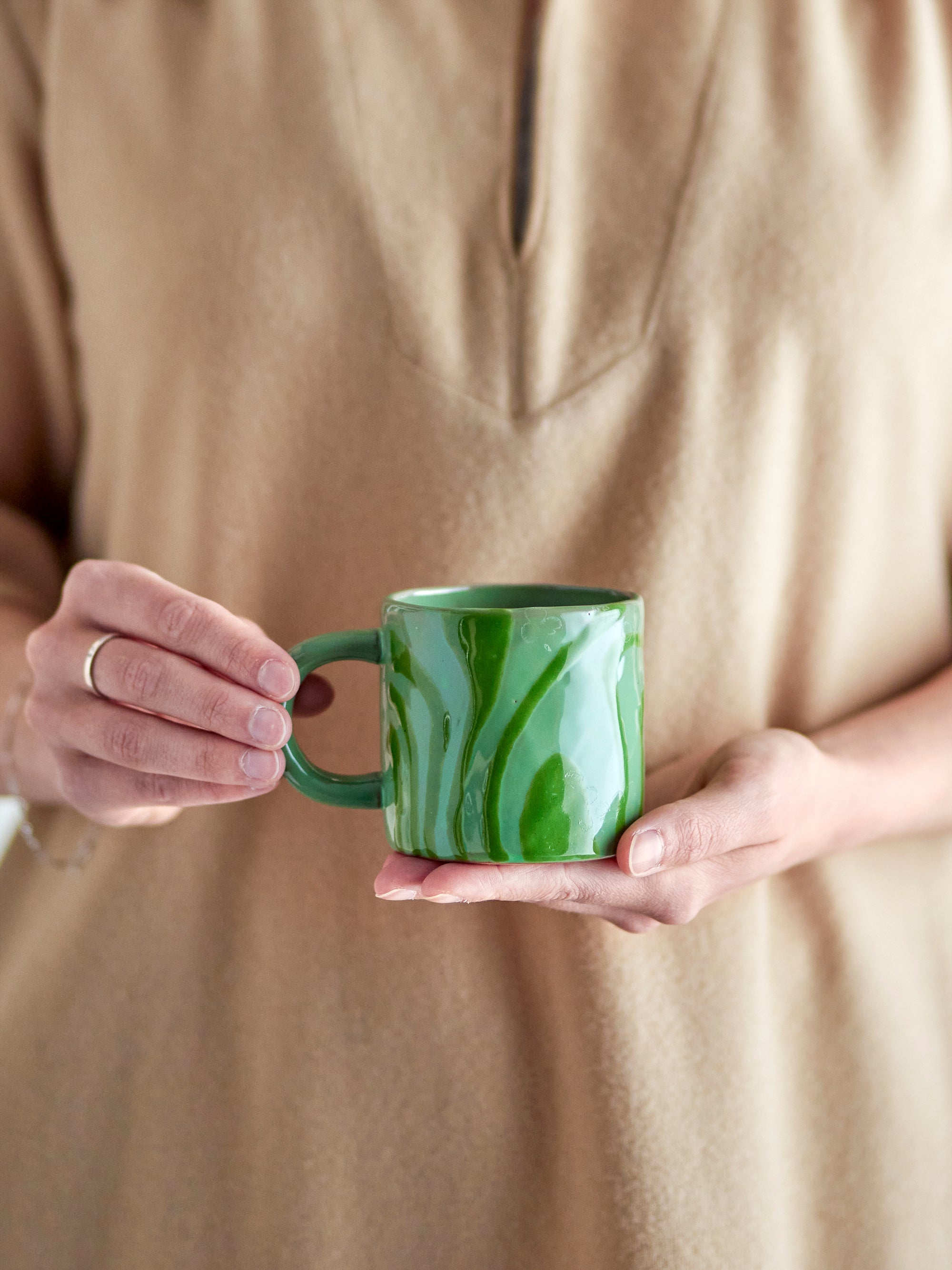 person holding green bloomingville ninka mug showing handmade swirl glaze
