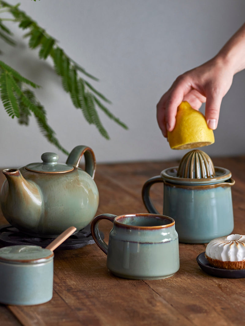 person squeezing lemon on green bloomingville pixie stoneware juicer