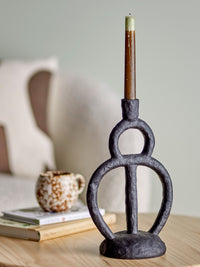close up of ramina candle holder in black polyresin on table with lit candle
