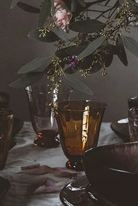 Boule amber glasses by Olsson & Jensen on a moody dinner table with foliage