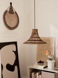 Living room corner with a woven pendant lamp, abstract artwork and a Sonja pedestal on a low shelf
