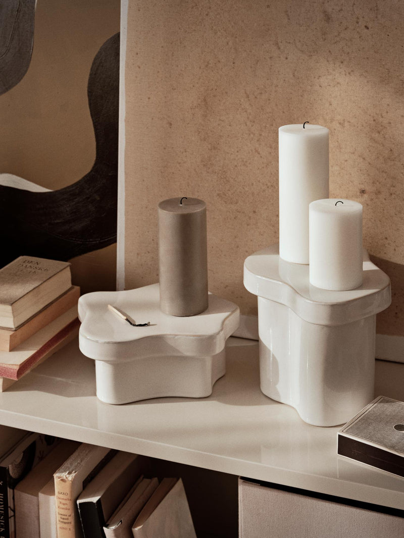 Off white Sonja pedestals displaying white and grey pillar candles on a shelf