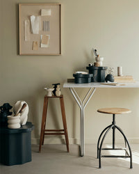 Black Sonja pedestals beside a small desk and stool in a light home workspace