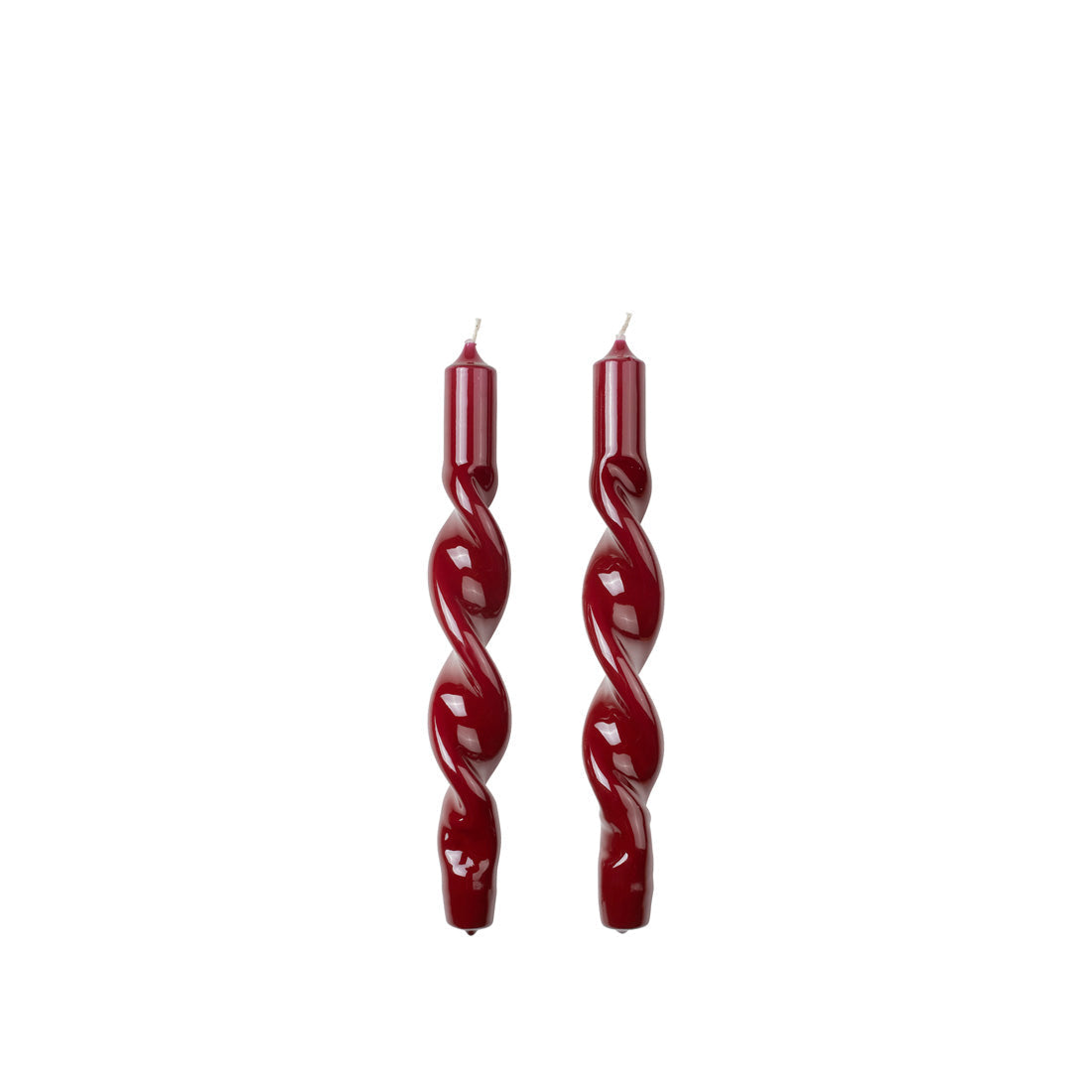 Two Broste Copenhagen glossy Twist Taper Candles in burgundy on a white background